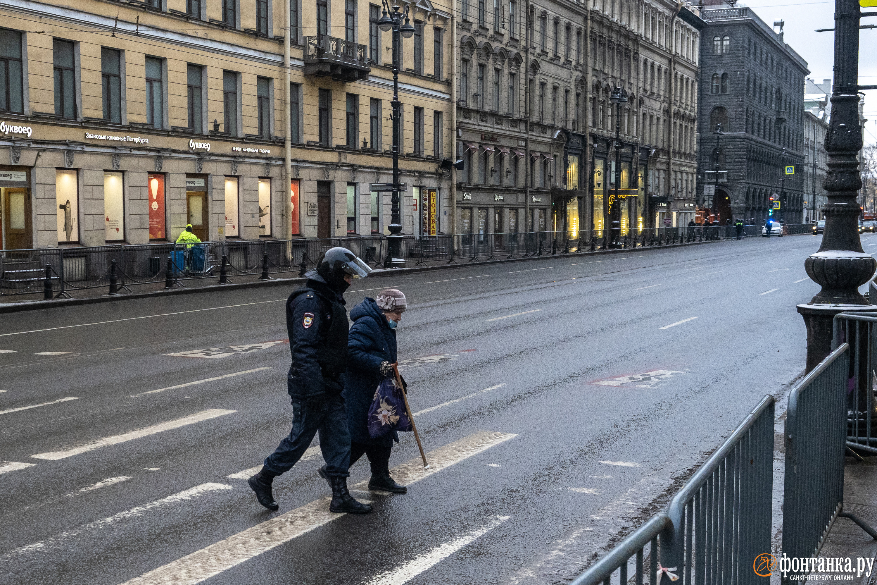 Полицейский переводит бабушку через перекрытый из-за протестных акций Невский проспект