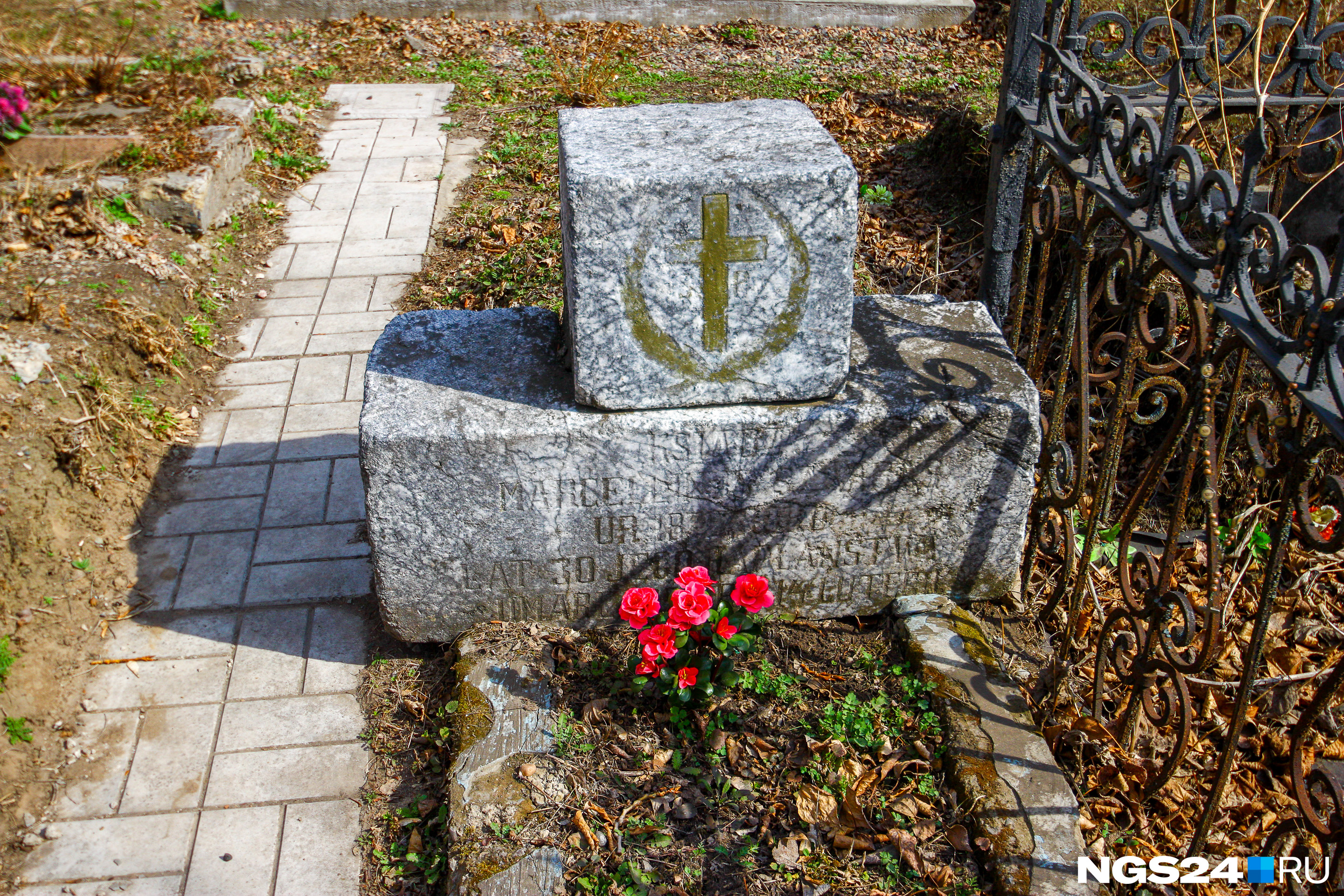 Надгробный камень с католическим крестом и полустершейся надписью