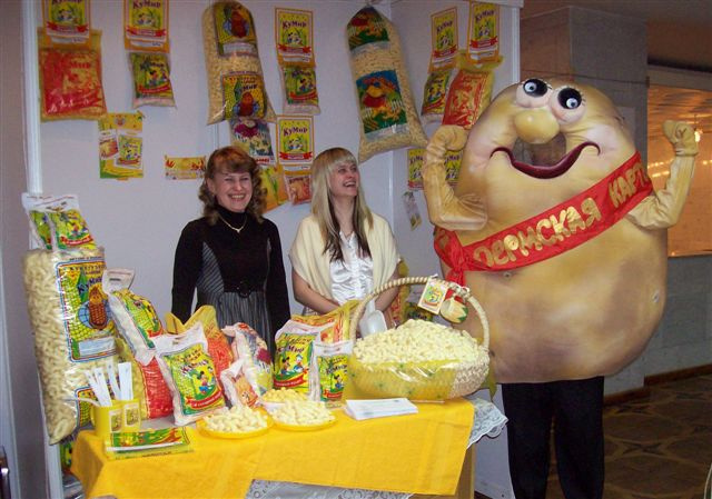 Человек-картошка на выставке рядом с еще одним пермским продуктом — кукурузными палочками