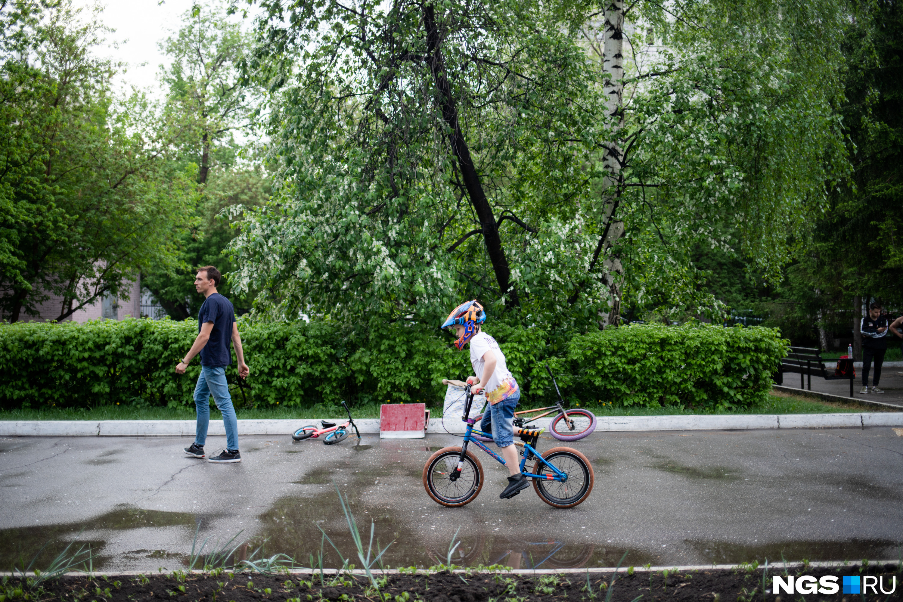 Дети в парке катаются по дорожкам на велосипедах