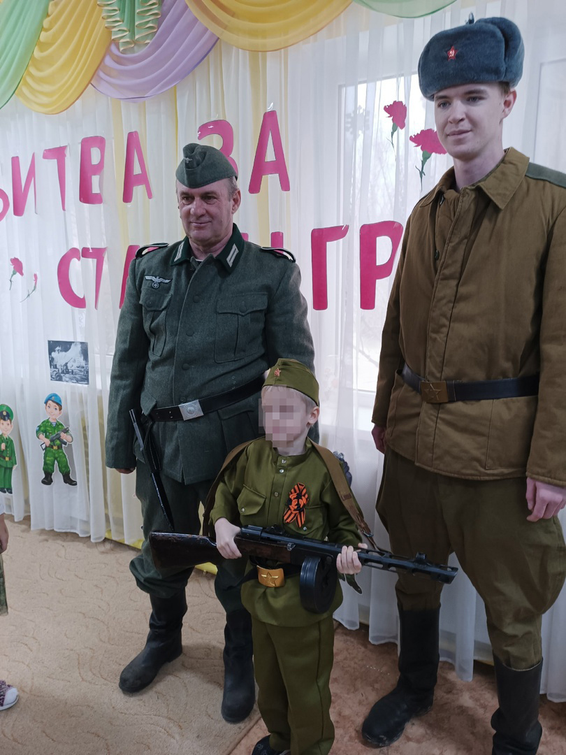 Улыбающийся мужчина в костюме солдата вермахта фотографировался с детьми рядом с советским солдатом