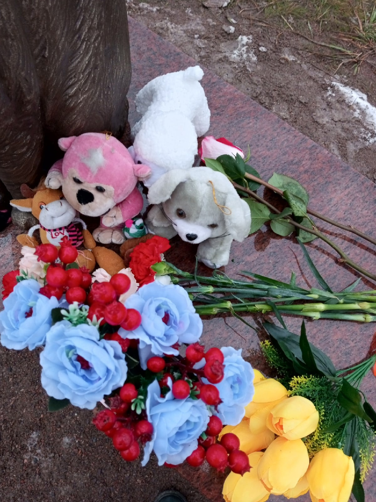 Кроме цветов рядом с памятником лежат игрушки — как для маленького ребенка