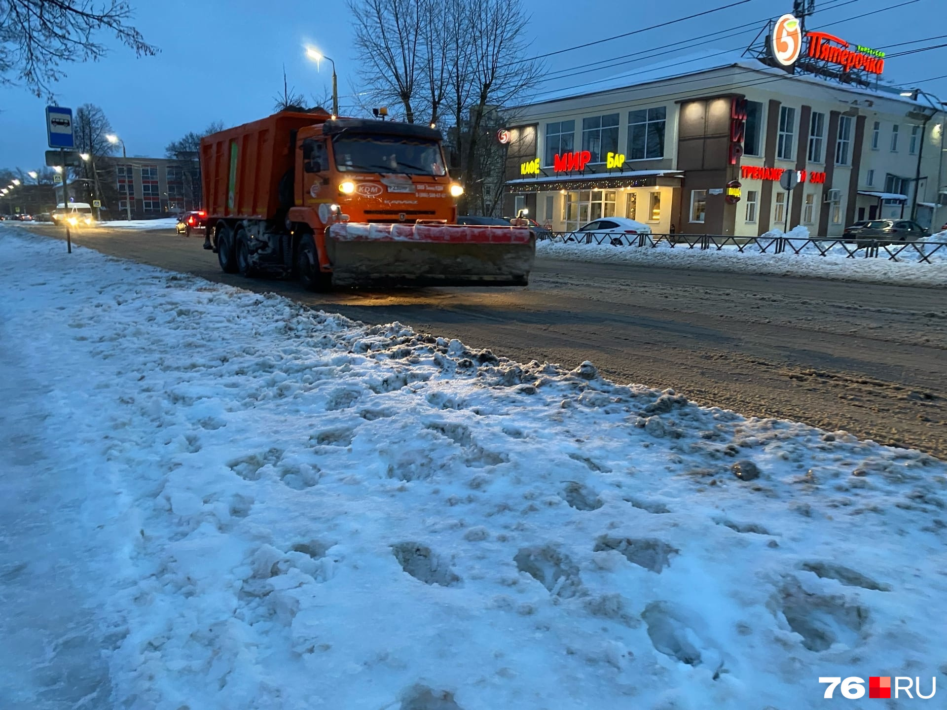 Снегоуборочная машина проехала по заснеженной дороге с поднятым ковшом