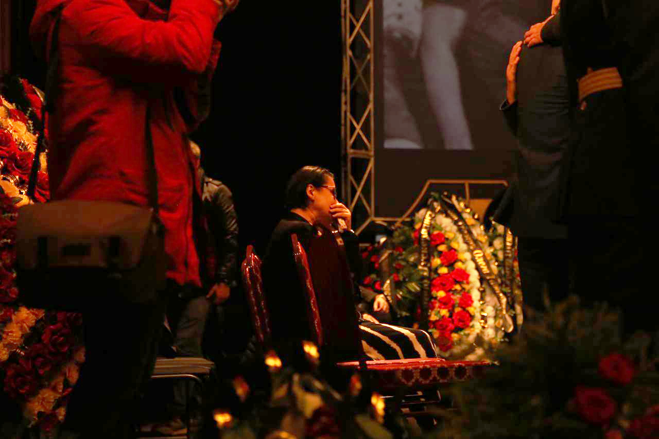 Супруга Сергея Пускепалиса Елена по-прежнему сидит в первых рядах у сцены с гробами
