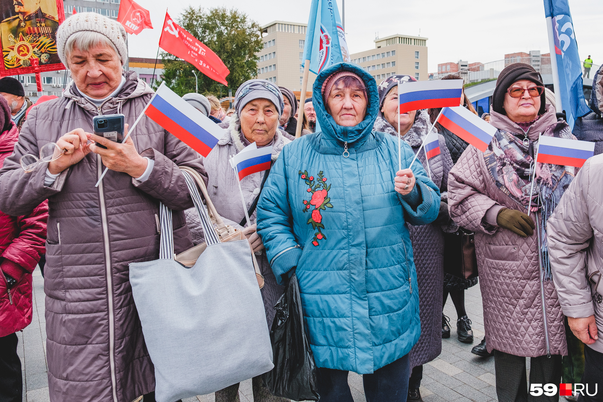 Митингующие держат флажки России и флаги партий Митингующие держат флажки России и флаги партий