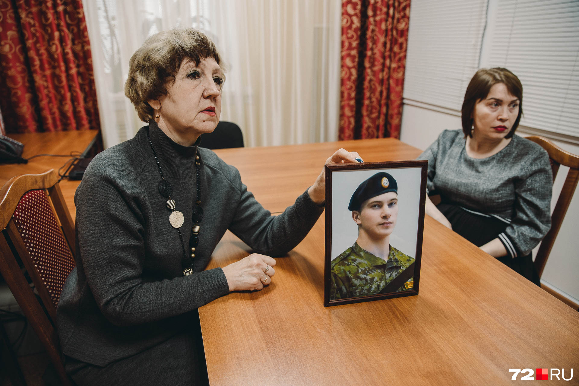 Глава села и классный руководитель бережно держат посмертный портрет погибшего военного