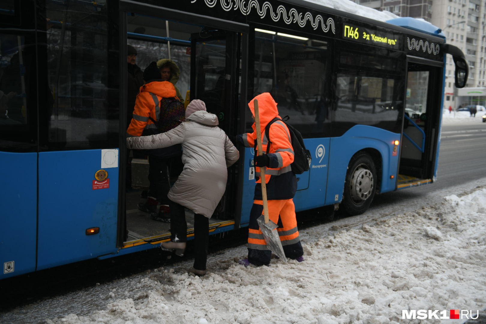 Дворники помогают бабушке забраться в автобус
