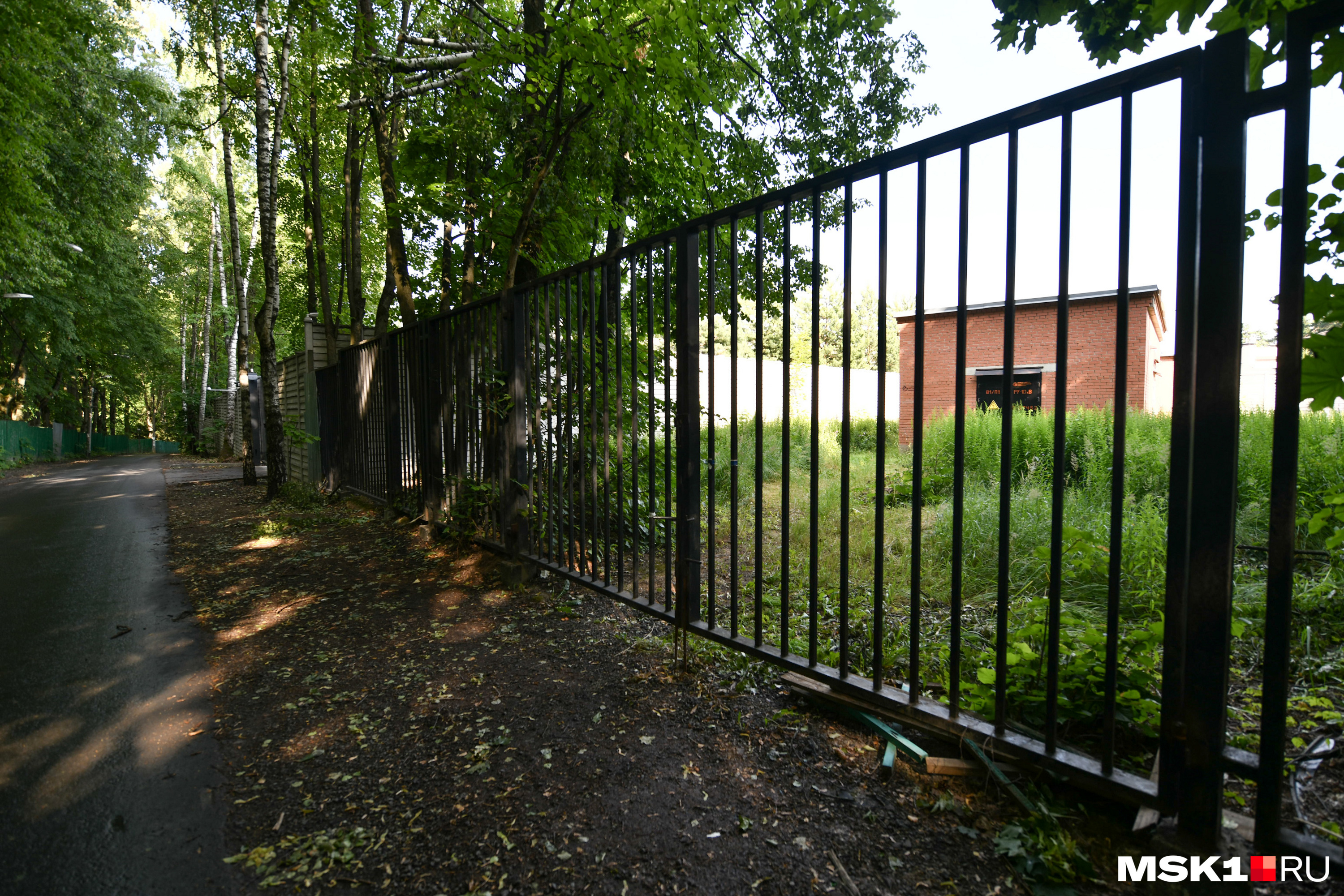 В нескольких метрах от домов олигархов всё выглядит намного беднее — стоит обычный забор, как в спальном районе любого российского города