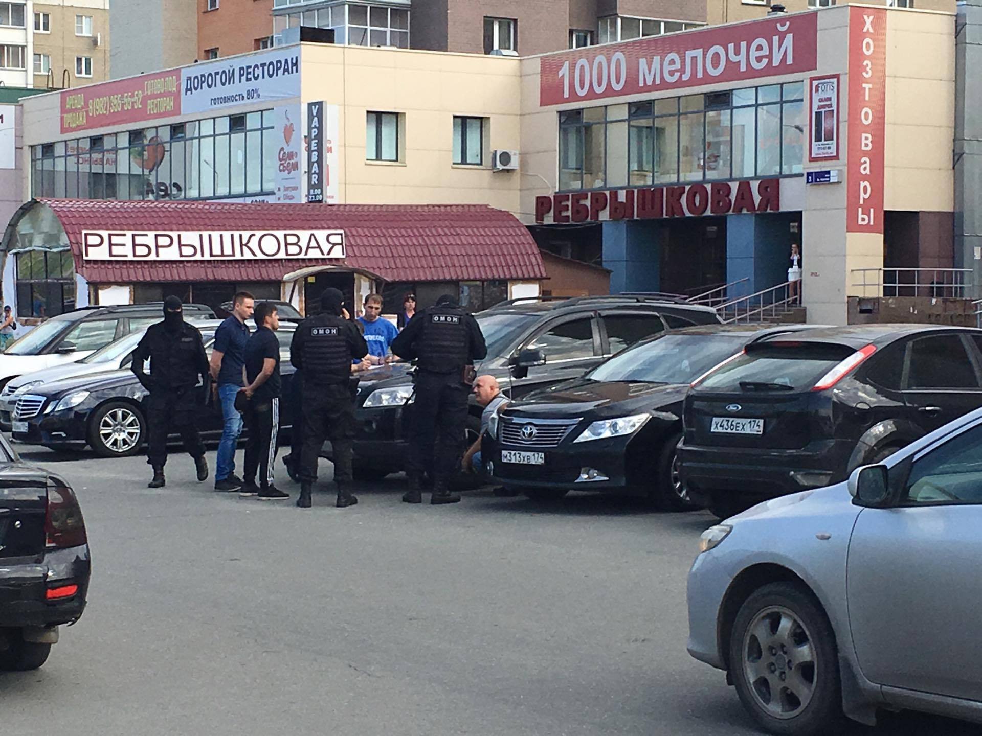Мужчина, сидящий на корточках, разряжает пистолет в присутствии ОМОН