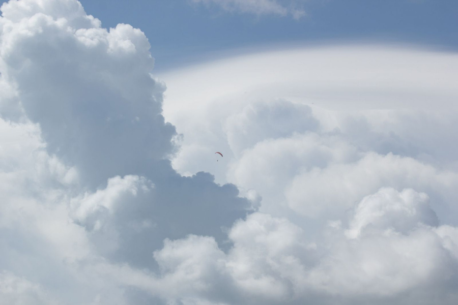 Маленькая точка по центру кадра – человек на параплане. На фоне облаков он кажется совсем крошечным.