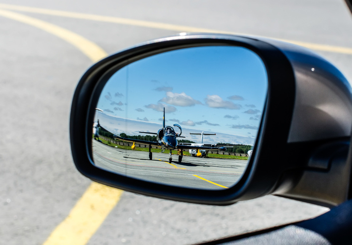Вид на самолет из зеркала заднего вида автомобиля сопровождения
