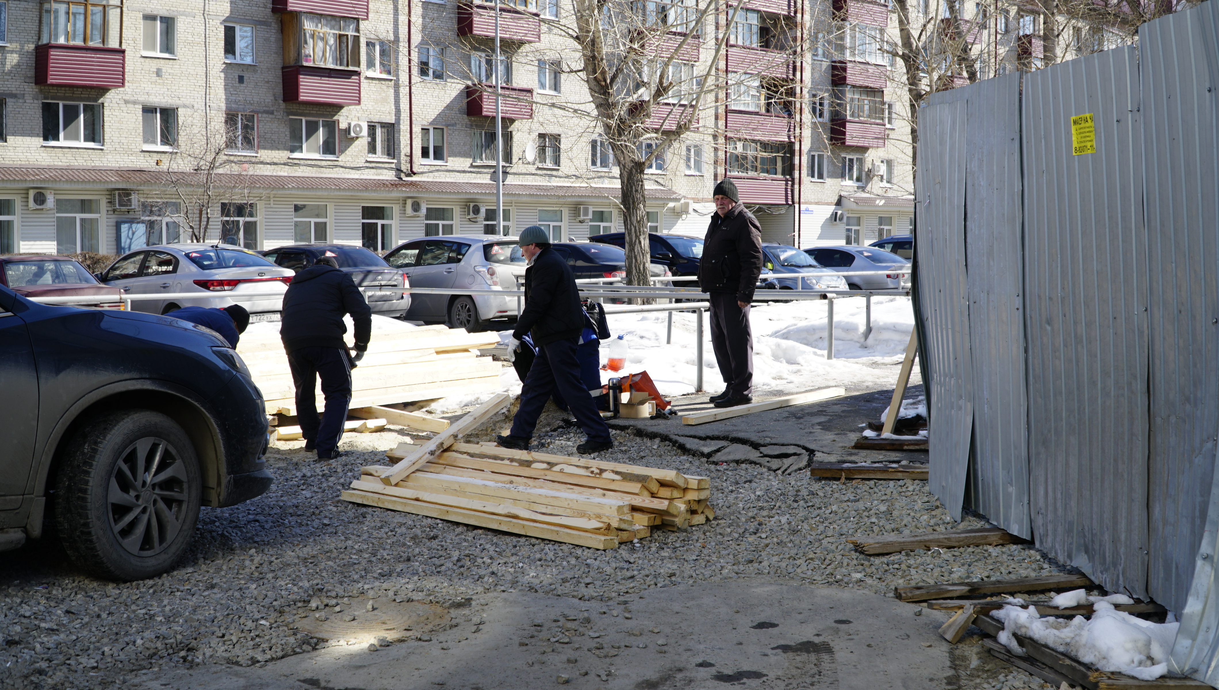 Рабочие пилят доски, чтобы огородить опасную зону Рабочие пилят доски, чтобы огородить опасную зону