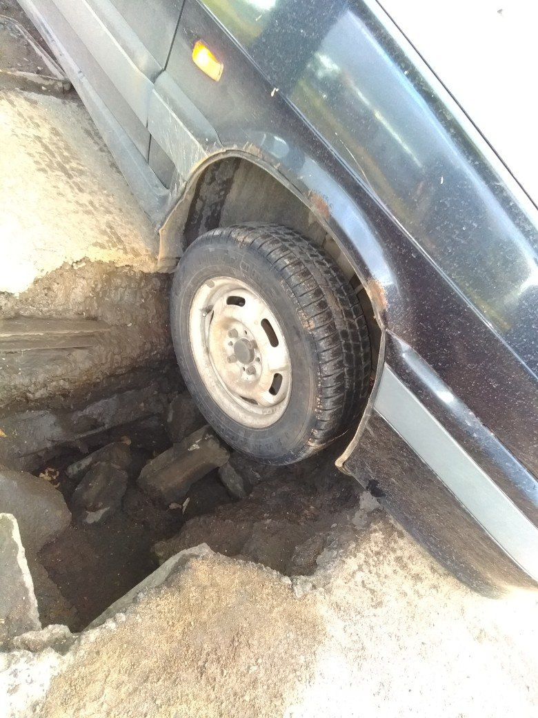 Машина провалилась в яму передним колесом.