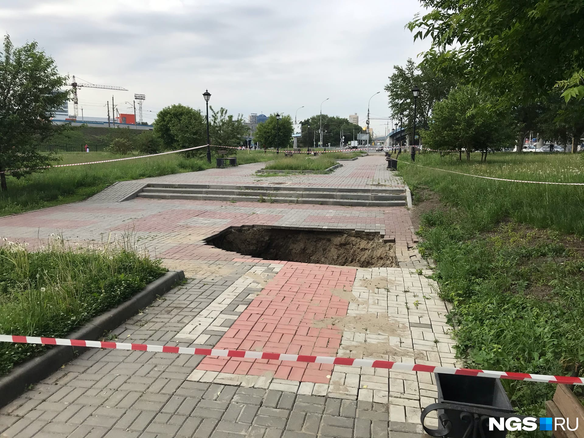 Яму оградили сигнальной лентой, но люди перелазят через неё и проходят по аллее Яму оградили сигнальной лентой, но люди перелазят через неё и проходят по аллее