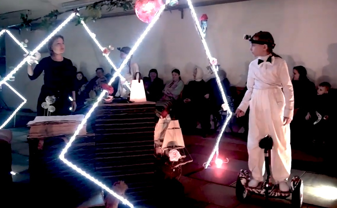 Кадр из спектакля «Амальгама», где дети-актеры катаются на гироскутерах