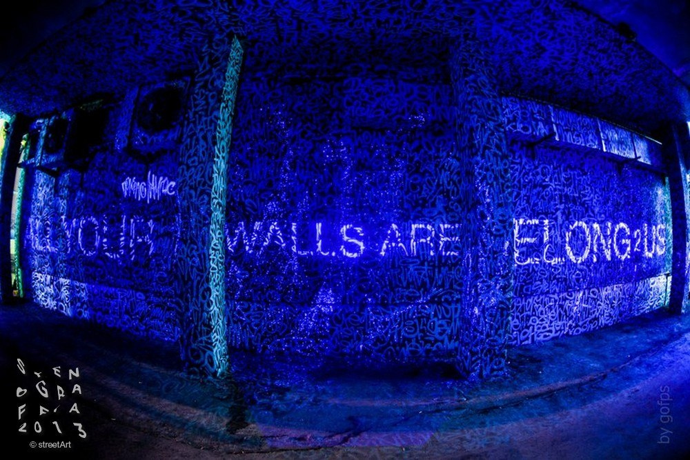 Под ультрафиолетом светится надпись «Все ваши стены принадлежат нам»