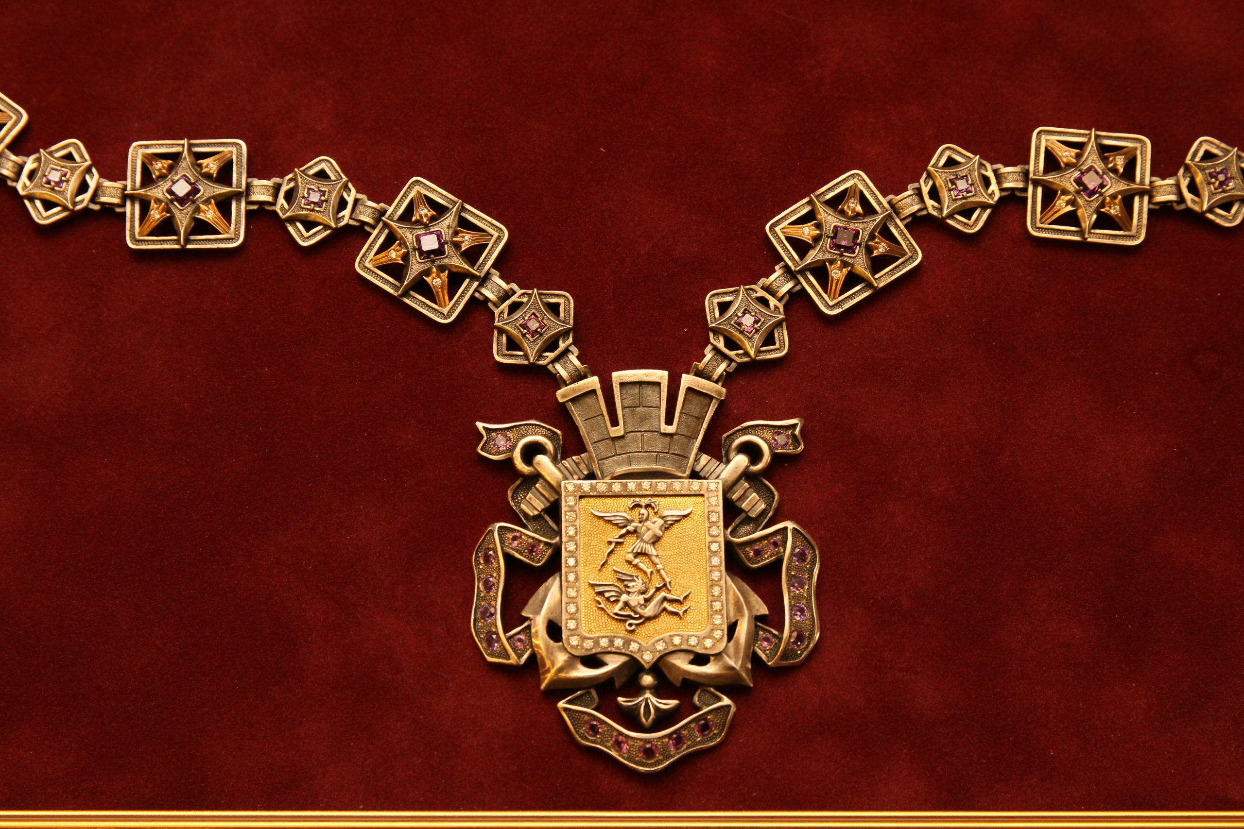 Знак украшен аметистами и фианитами, а поле герба — золотое