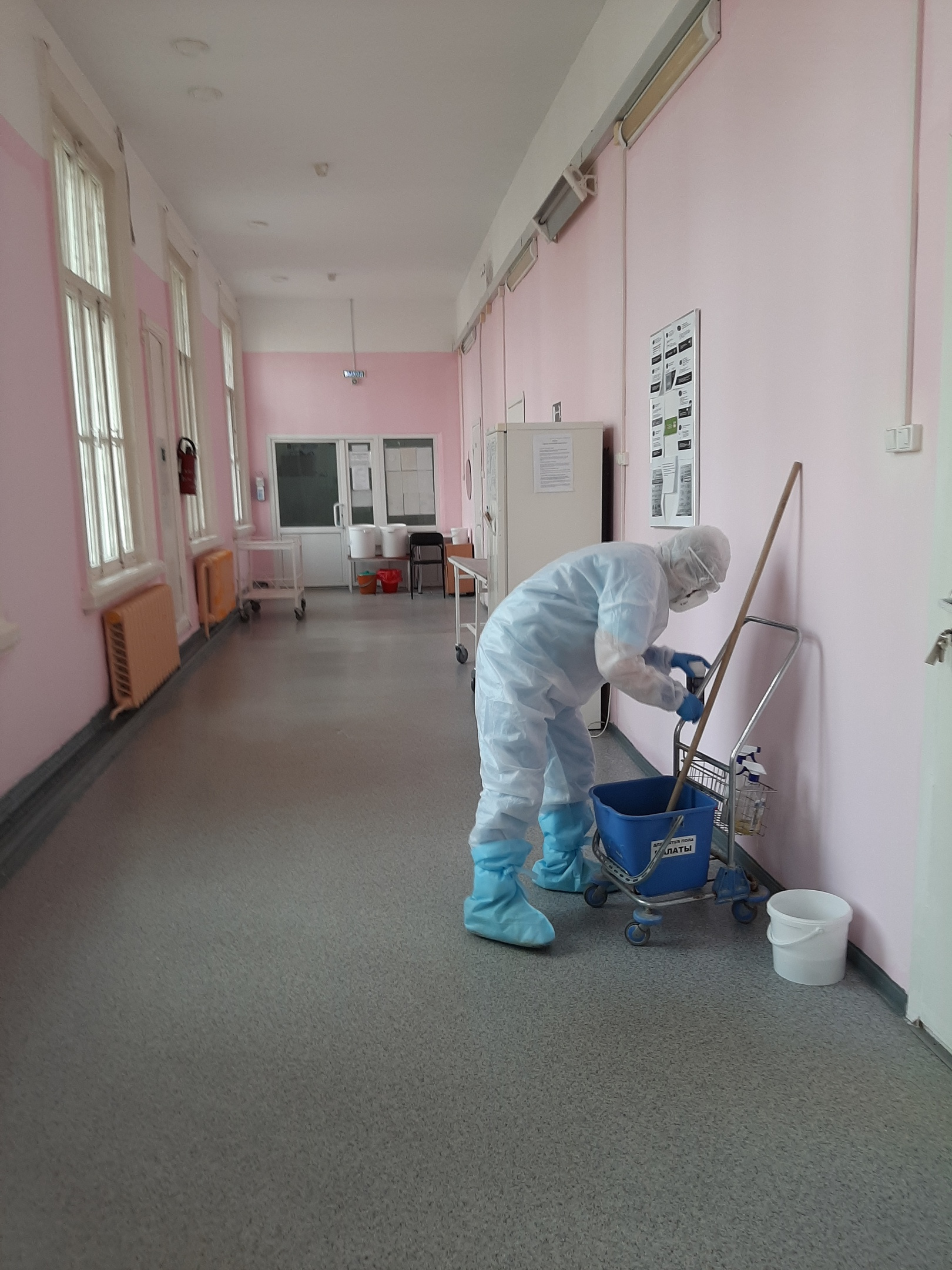 Сотрудник больницы делает уборку в защитном костюме