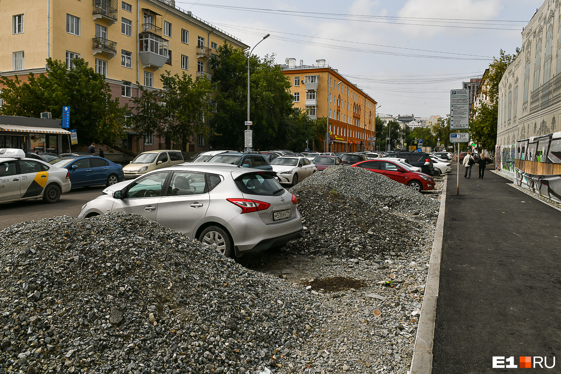 На парковке уже лежат кучи щебня, среди которых скромно стоят автомобили