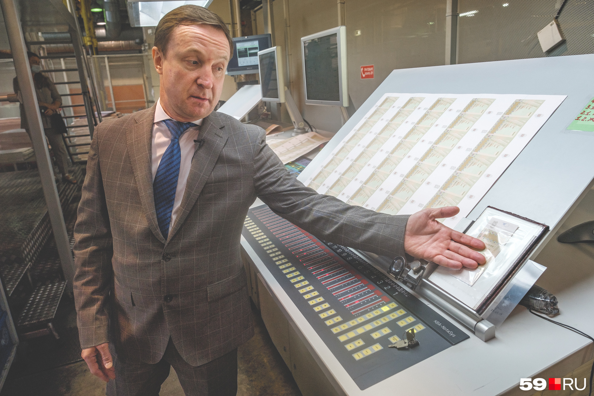 Директор фабрики Виктор Осетров показывает на образец, с которым сверяют изображение на отпечатанных листах