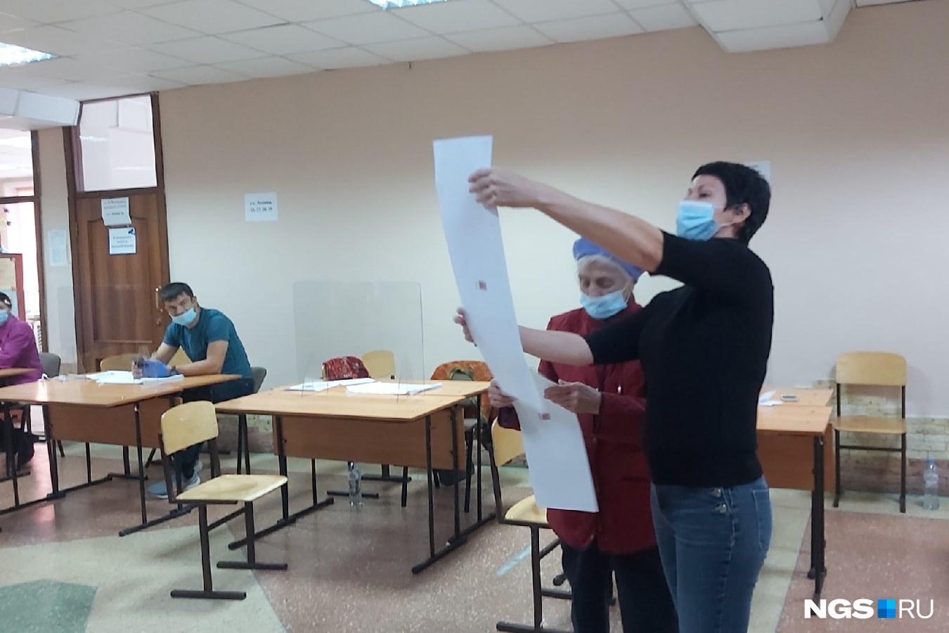 Участок в 10-й гимназии. Член комисии помогает бабушке разлядеть строки в бюллетене Участок в 10-й гимназии. Член комисии помогает бабушке разлядеть строки в бюллетене