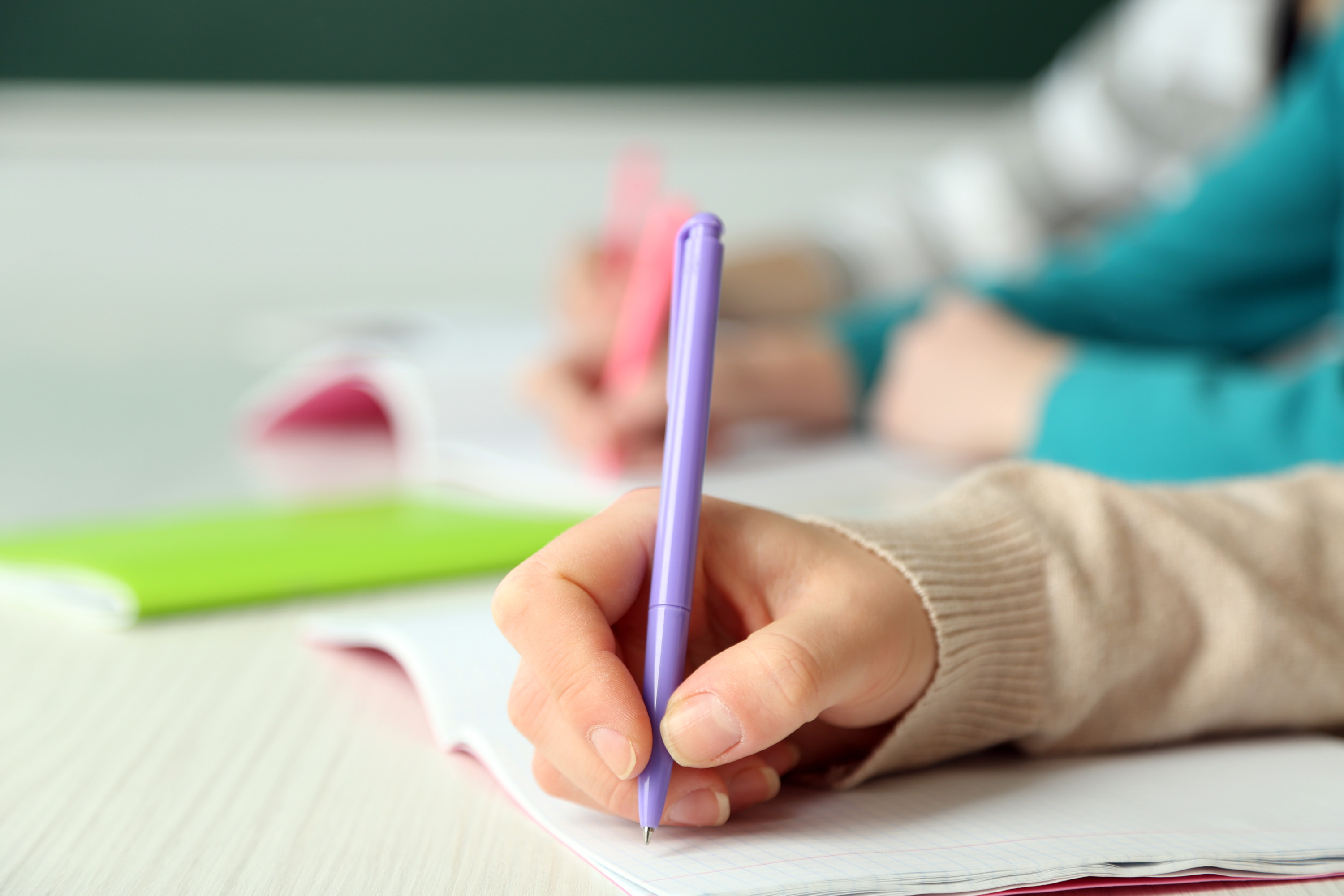 Write 2 4 5. Teacher hand on hand of pupil writing.