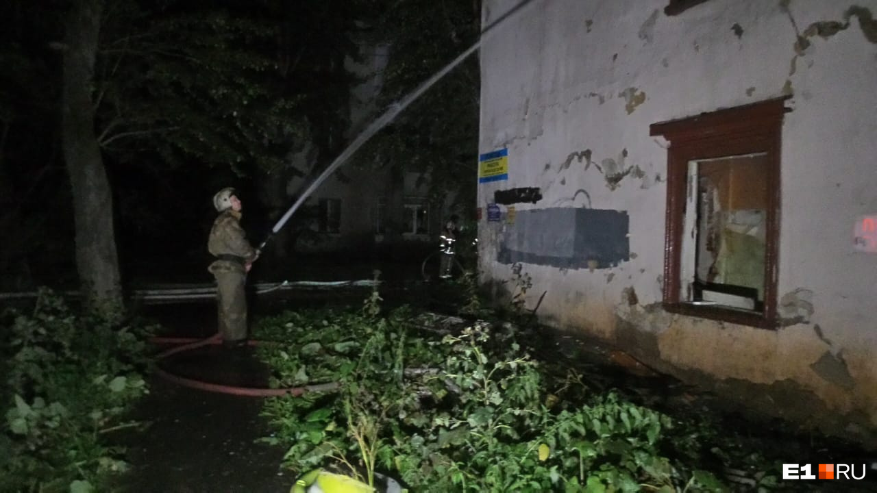 Пожарный заливает дом водой