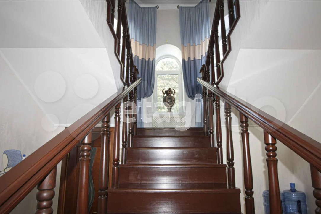 Красивое фото лестницы на второй этаж большого дома и то ли ваза, то ли скульптура, напоминающие безголовую женщину