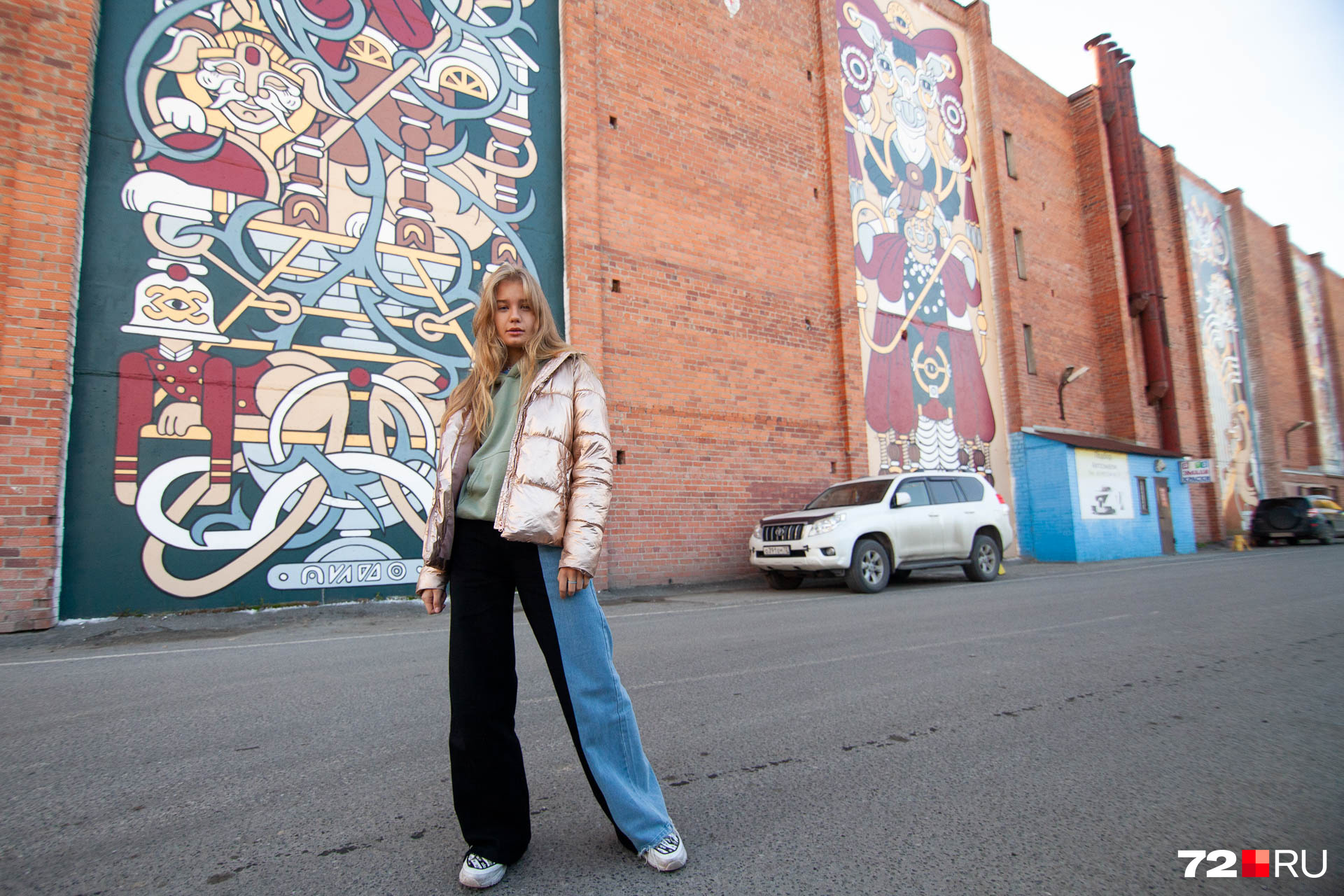 Лиза Артюхова (модель на фото) была одним из организаторов фестиваля уличного искусства. Она говорит, что здание, на котором нарисовано граффити, — это шиномонтажка. Рисовать на нем было непросто, потому что ежедневно приходилось контролировать машины, подъезжающие к стене