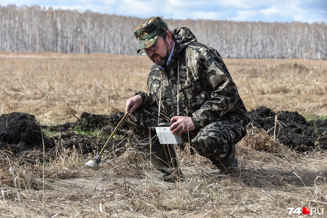 Олег Тарасов измеряет уровень бета-излучения в поле недалеко от распаханной защитной полосы