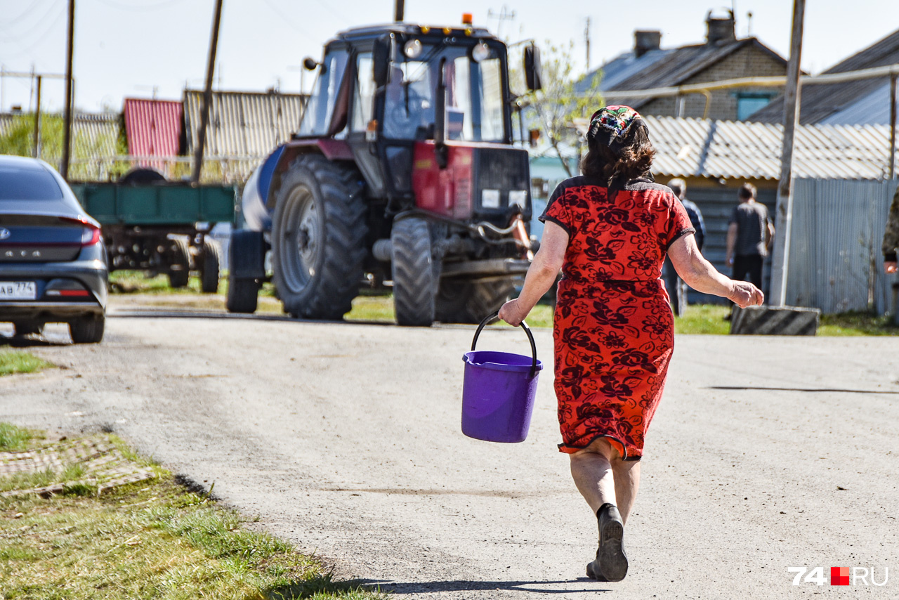 Жительница Шумаков спешит к трактору-водовозу