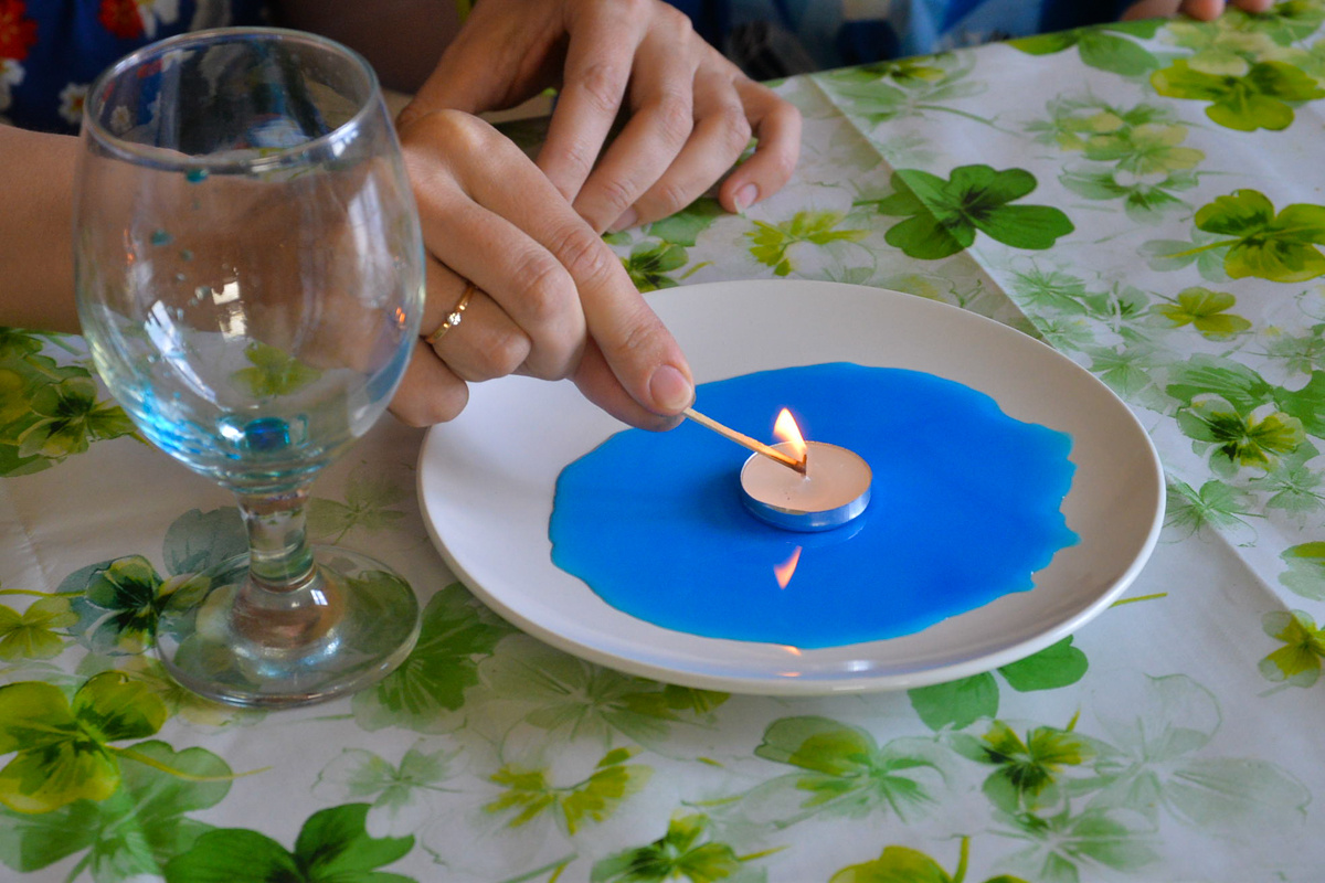 Размешиваем в воде пищевой краситель, выливаем его на тарелку и ставим в воду свечку