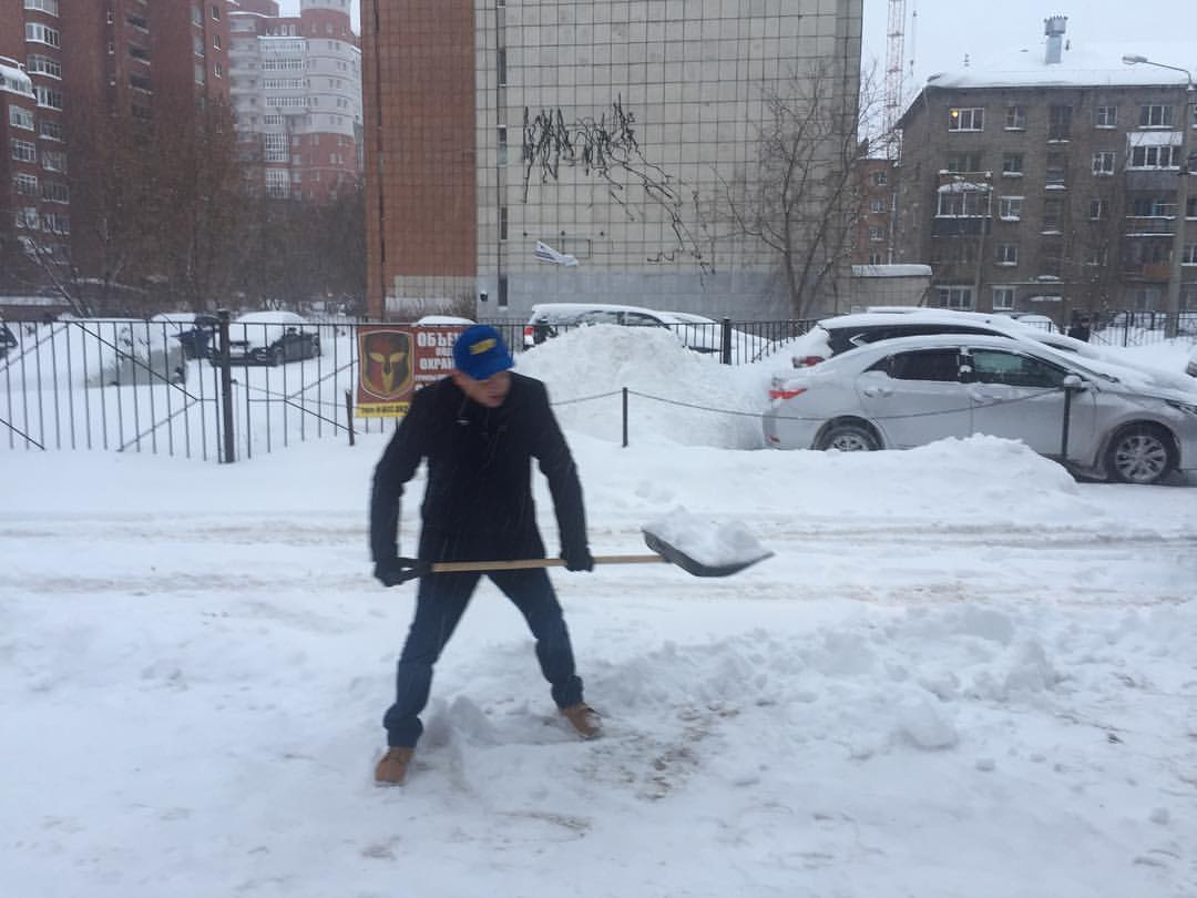 Олег Постников в кепке с символикой своей партии работает лопатой