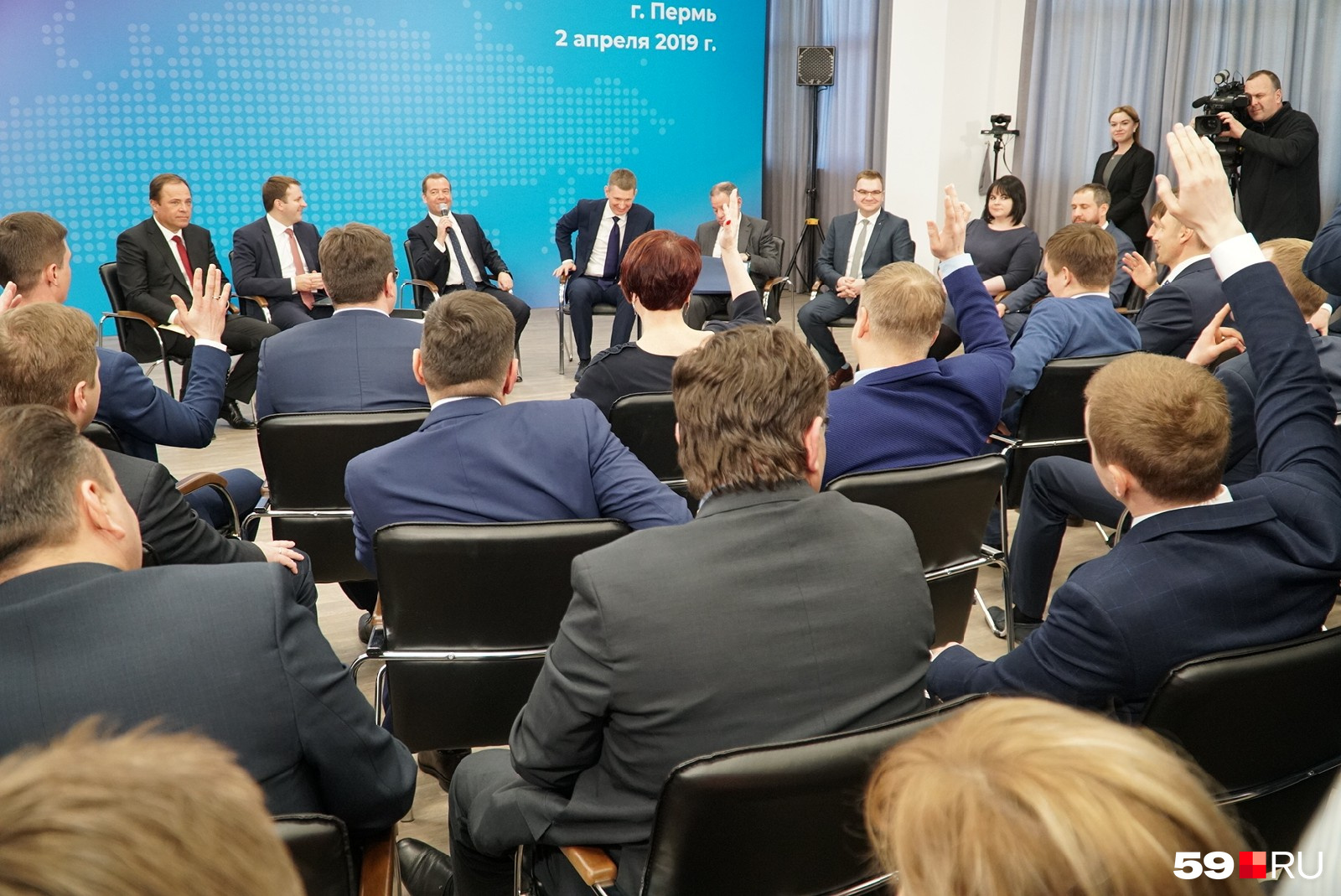 Чтобы задать вопрос, собравшиеся тянут руку Чтобы задать вопрос, собравшиеся тянут руку