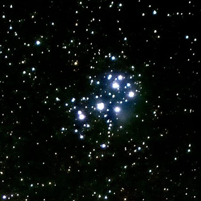 Плеяды крупным планом. Вокруг видно голубое свечение — это туманность, в которой зарождаются новые звезды