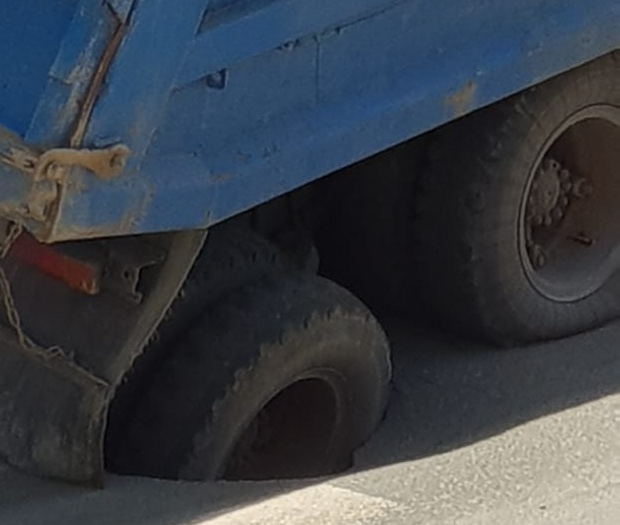 Заднее колесо грузовика увязло в глубокой яме