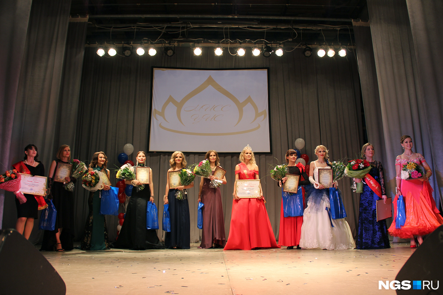 11 участниц сибирского этапа конкурса «Мисс УИС»: победительница — в красном платье в центре, первая и вторая мисс — с красными лентами