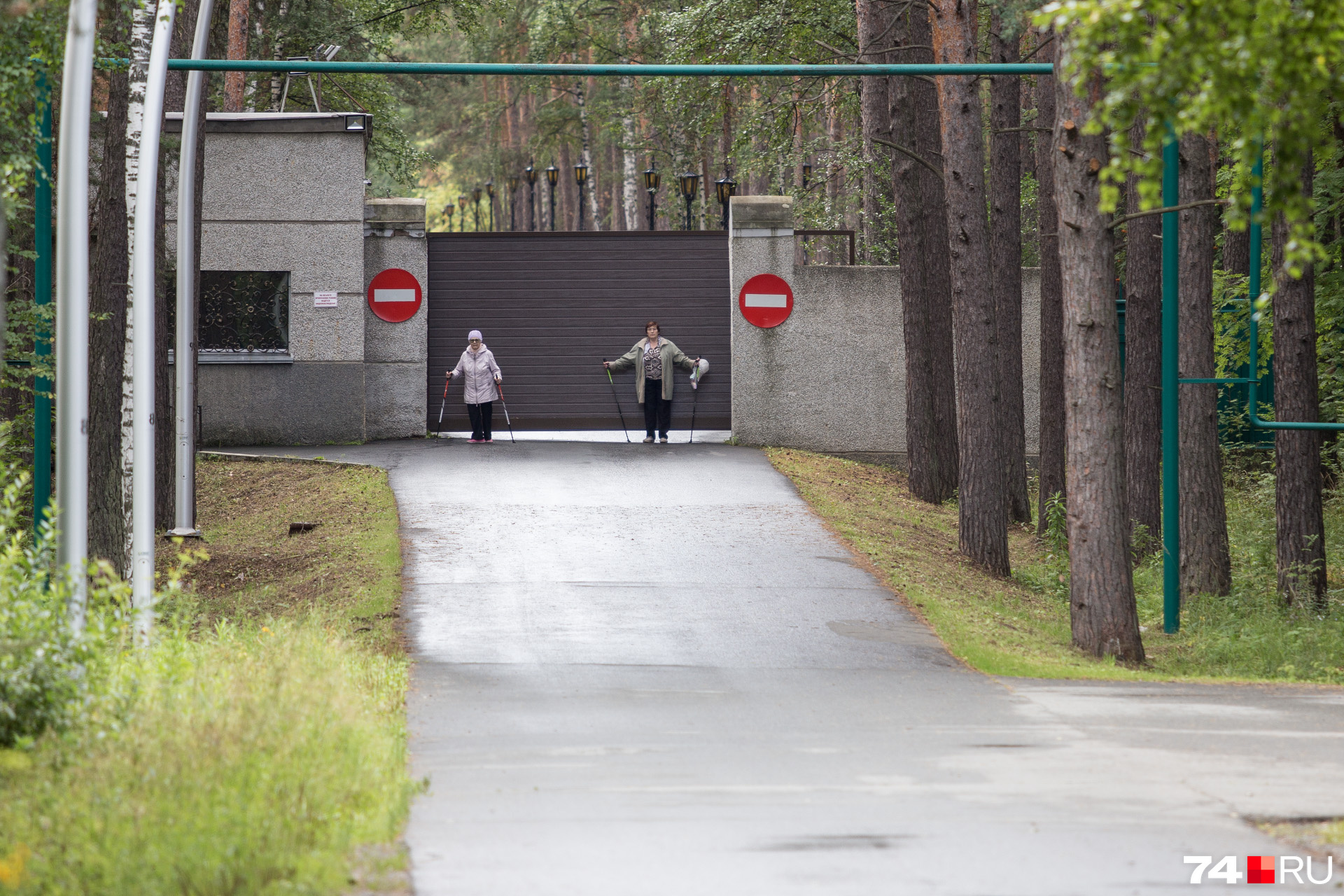Любительницы скандинавской ходьбы отдыхают, облокотившись на ворота губернаторского комплекса