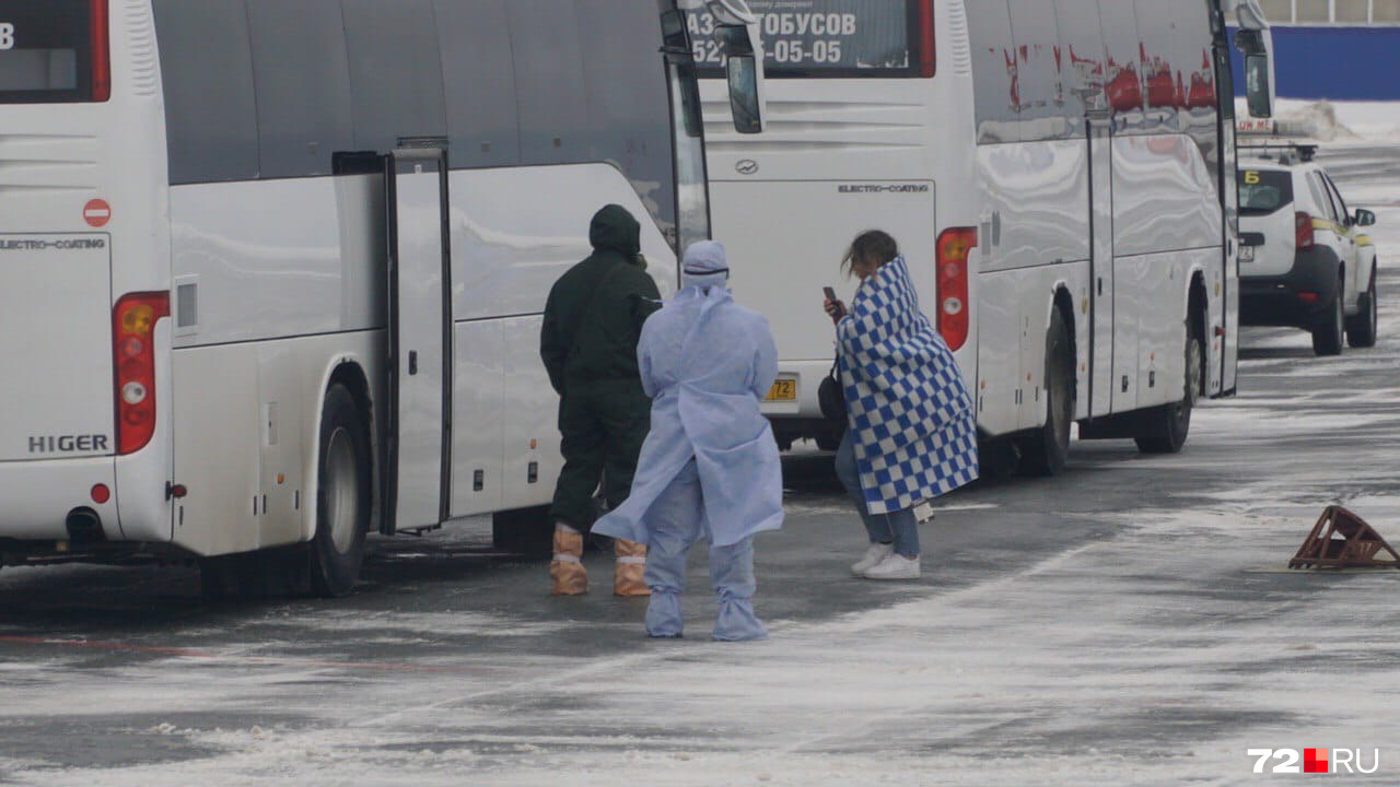 Пассажиры в одеялах заходят в автобусы. Всем им измерили температуру, теперь они отправляются в реабилитационный центр в посёлке Винзили