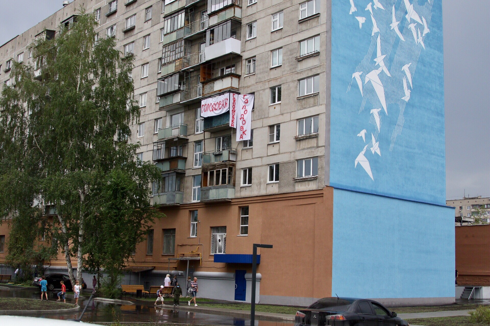 С одной стороны дома на Карла Маркса, 164 теперь памятные граффити, а с другой —  растяжка о голодовке