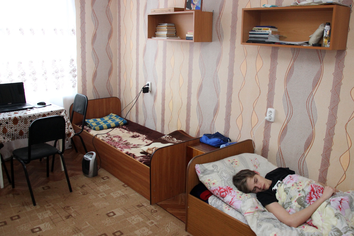 Трёхместная комната юношей, один из которых лег отдыхать после сложного экзамена