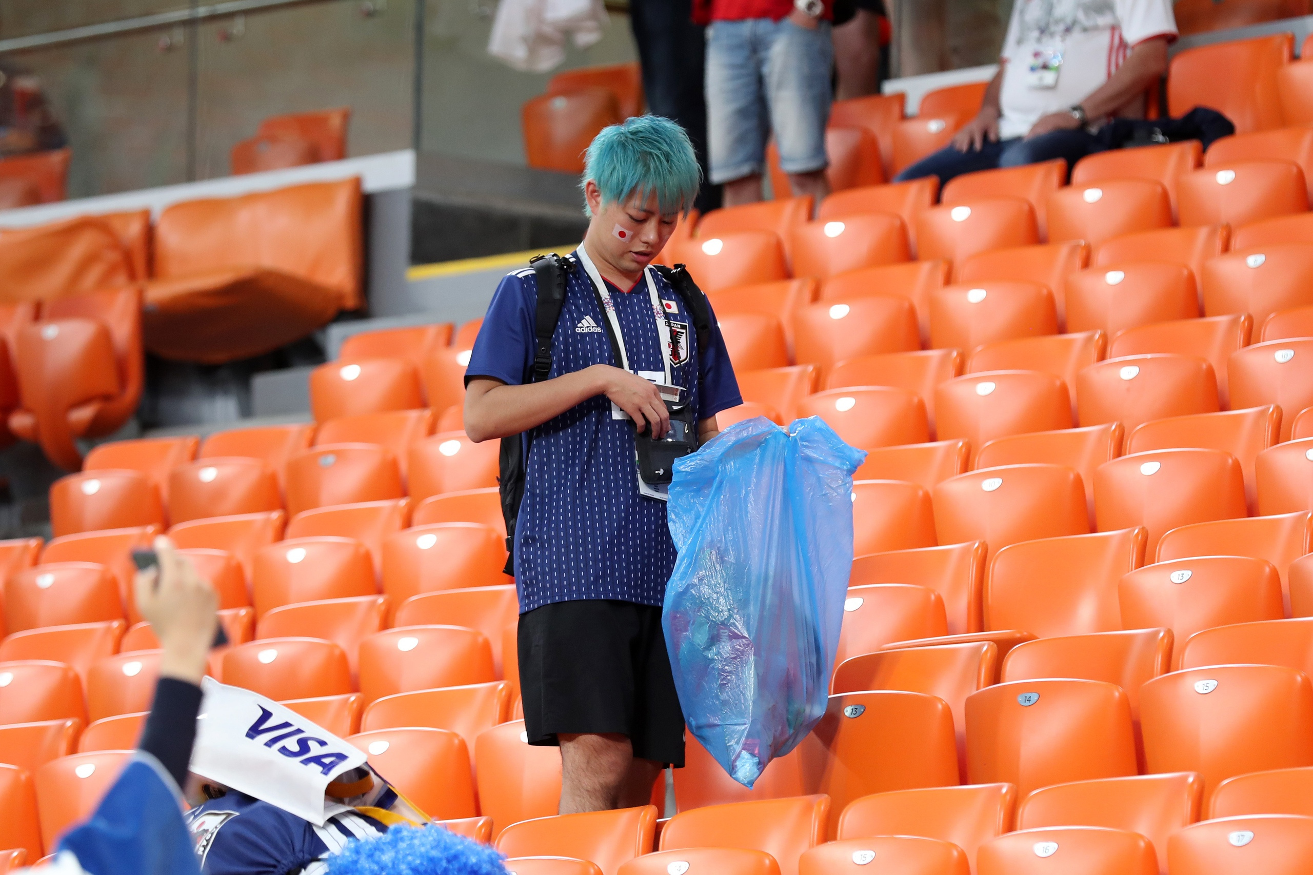 Японец собирает мусор в пакет почти под цвет его волос