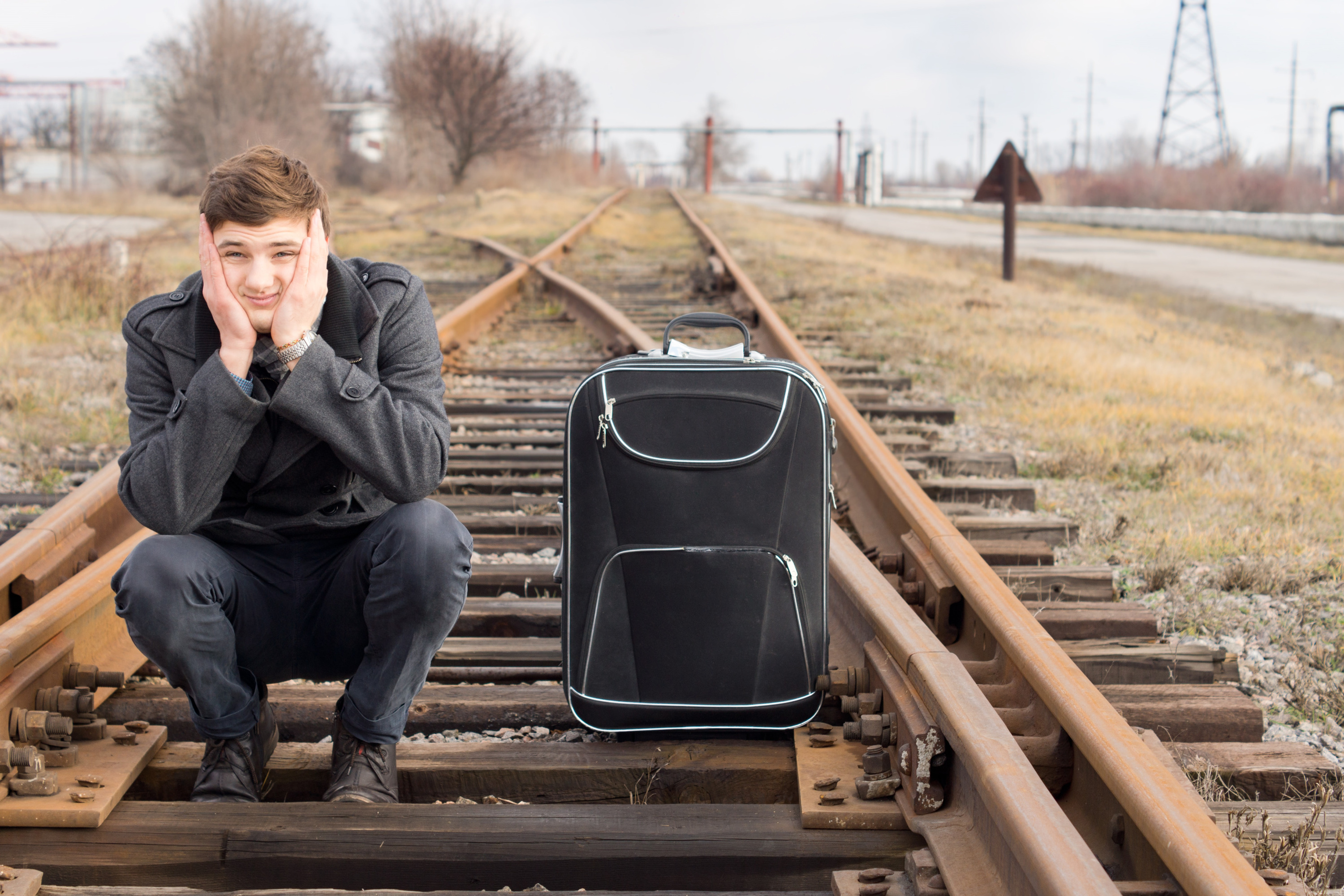 Сын переезжает в другой город. Мужчина уезжает. Парень уезжает. Человек ждет поезд. Фотосессия на железной дороге.