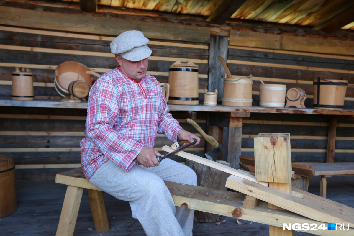 Бондарь показывает туристам, как делались деревянные бочонки