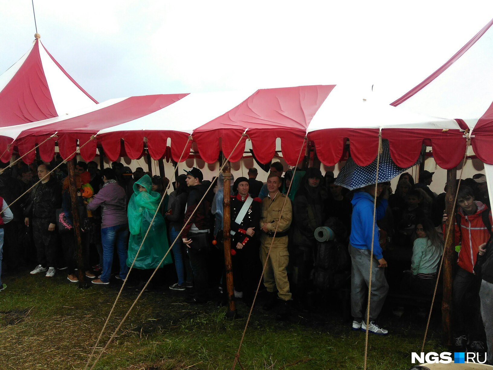 Участники фестиваля и зрители спасаются от дождя