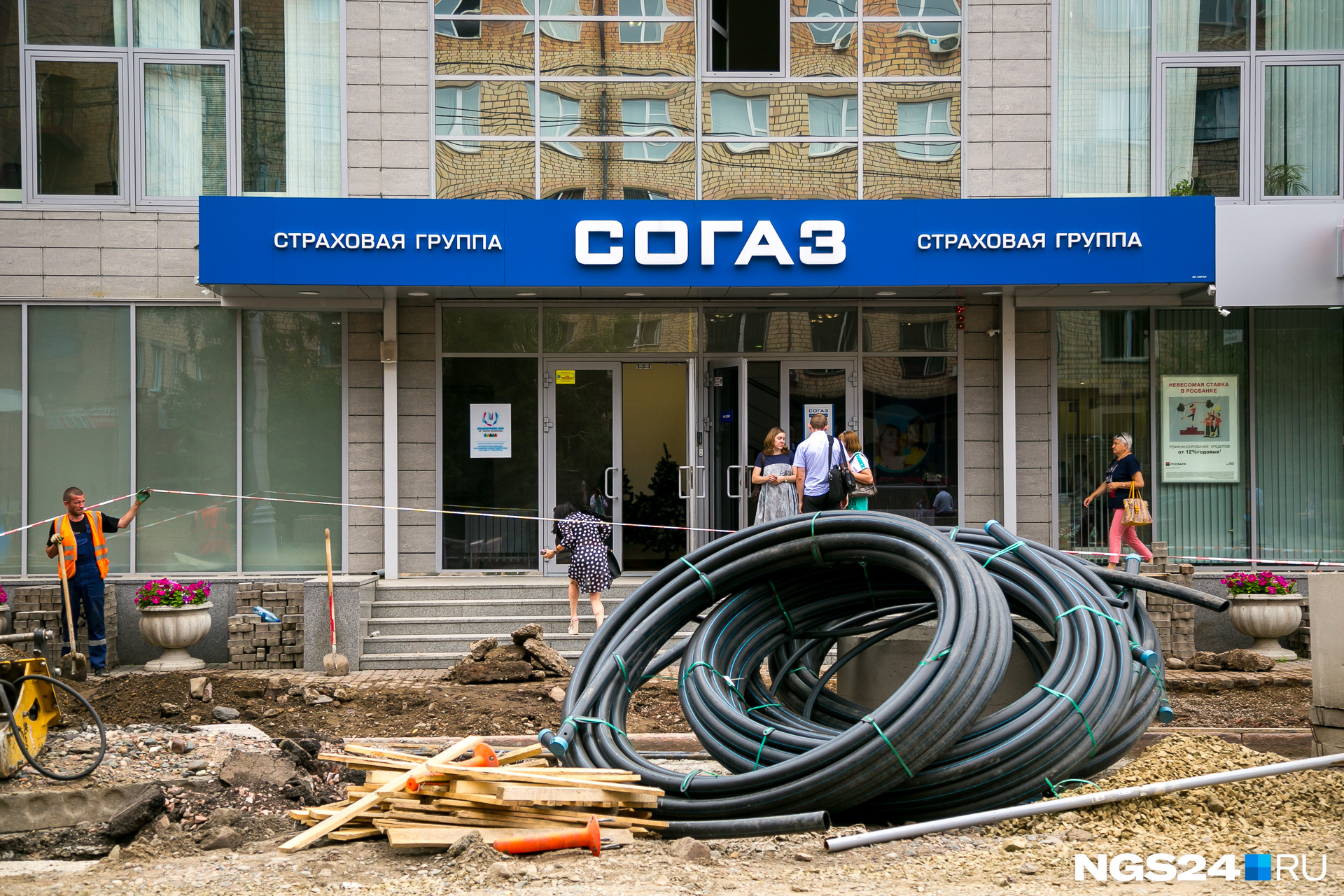 Одновременно с дорожными работами идёт и замена инженерных сетей. Попасть в здание можно, только подняв ленточку ограждения Одновременно с дорожными работами идёт и замена инженерных сетей. Попасть в здание можно, только подняв ленточку ограждения