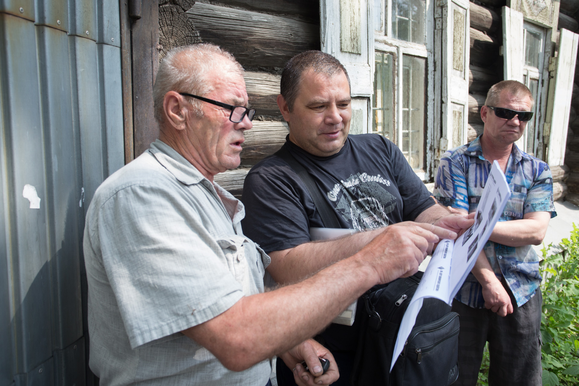 Дмитрий (в центре) показывает оценку его дома, но на фото — не его участок и не его строение