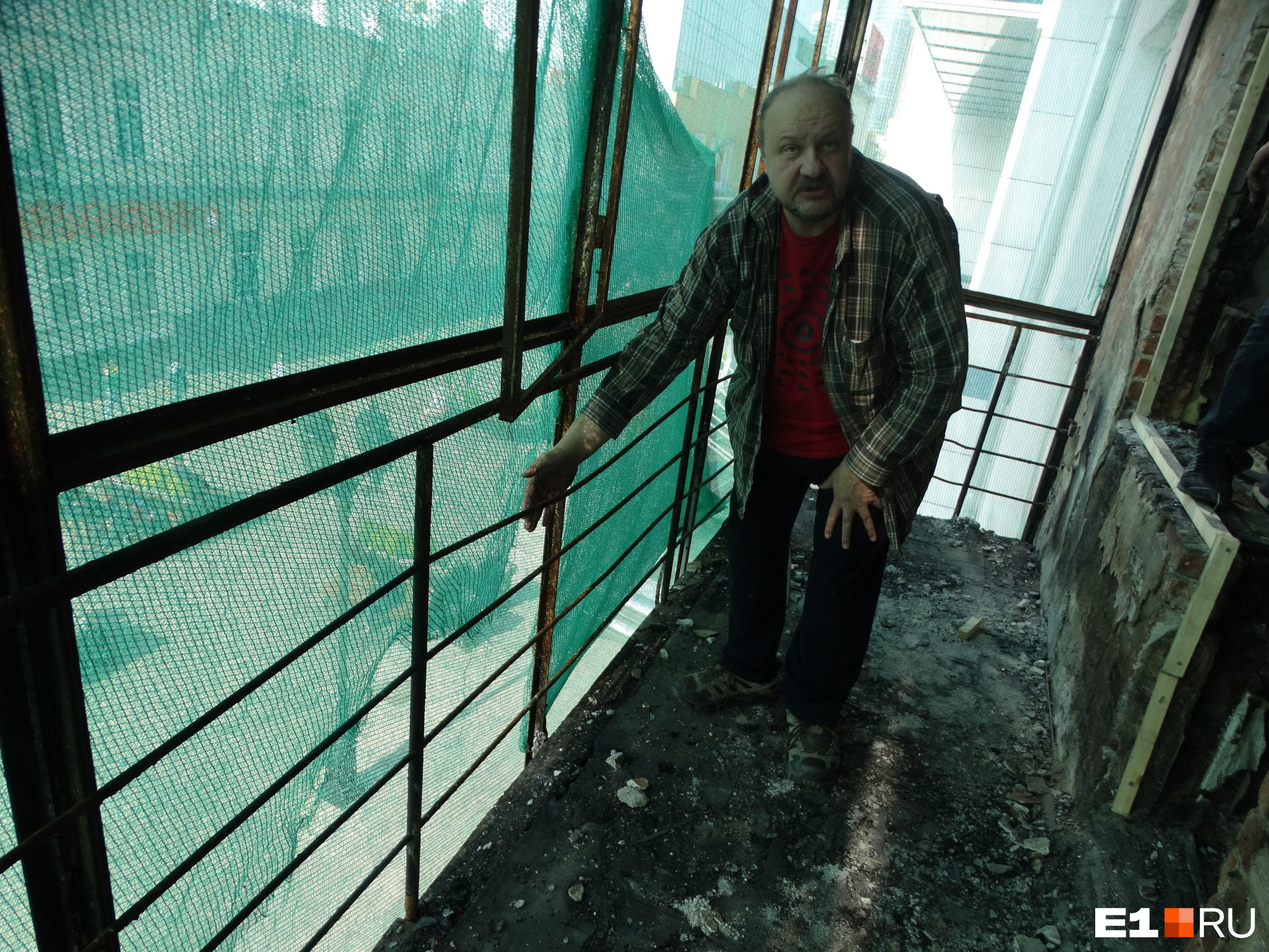 Мужчина показывает, что окурок или какой-то другой горящий предмет мог залететь на его балкон — в пространство между стеклами и ограждением 