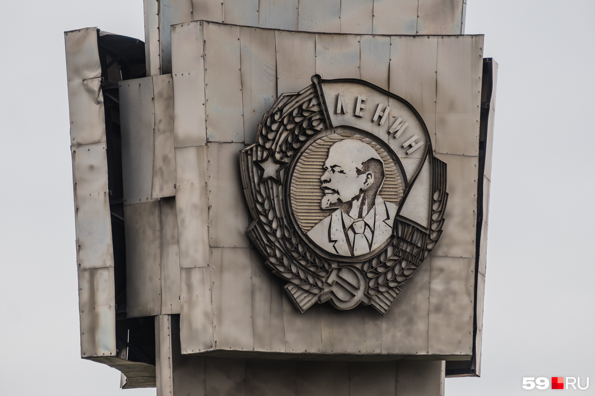 Стелу украшают Орден Ленина и лозунги