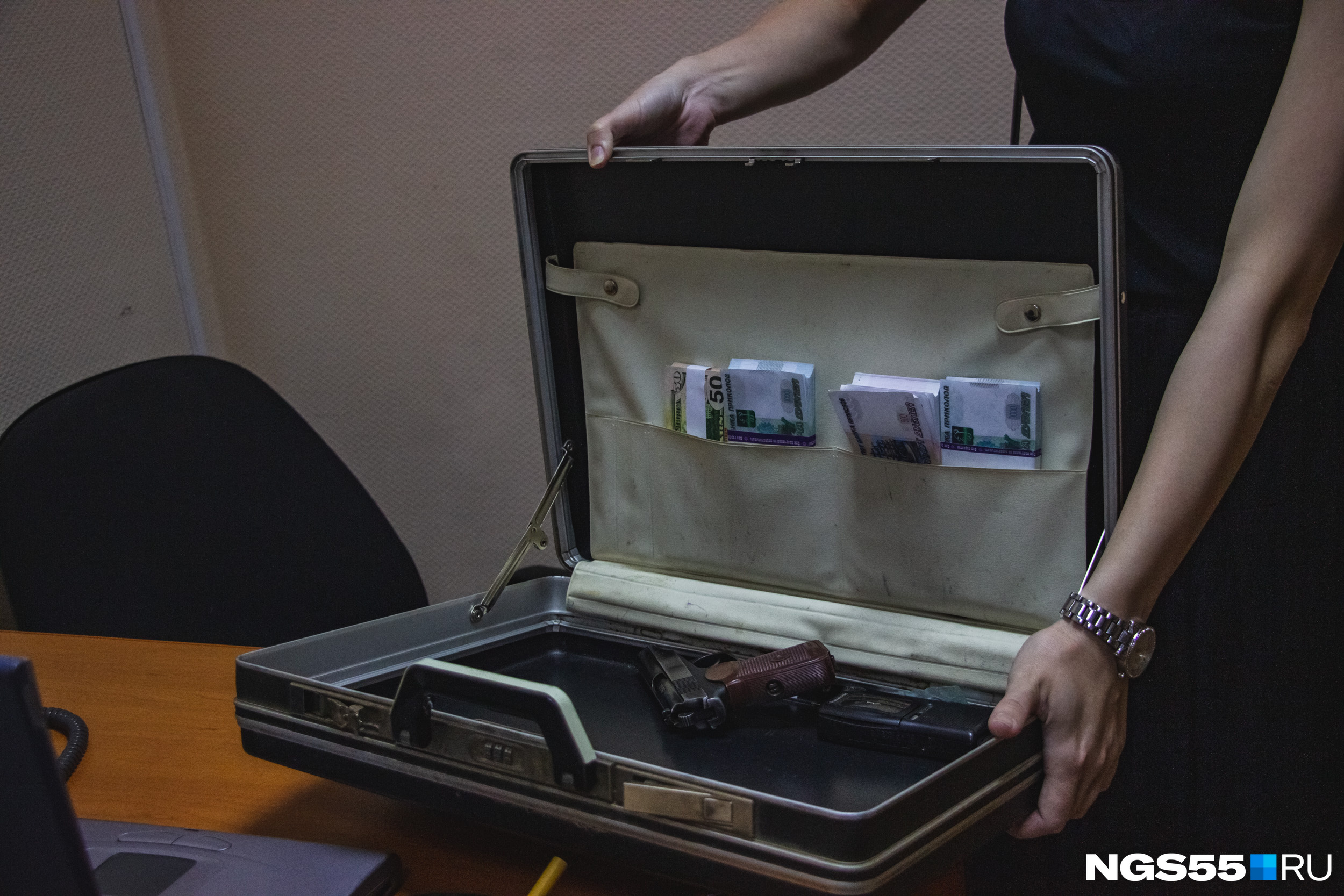 Под столом следователи находят чемодан с оружием и деньгами